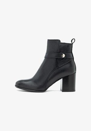 Czarny skórzany botek za kostkę z okrągłym noskiem, detalami w postaci pasków po bokach oraz słupkowym obcasem. Posiada pętelkę ułatwiającą zakładanie oraz gładką fakturę.