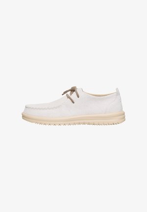 Zapatos de ante blancos con punta redondeada, suela de goma beige y dos cordones marrones. Presenta detalles de costura a lo largo de los bordes.