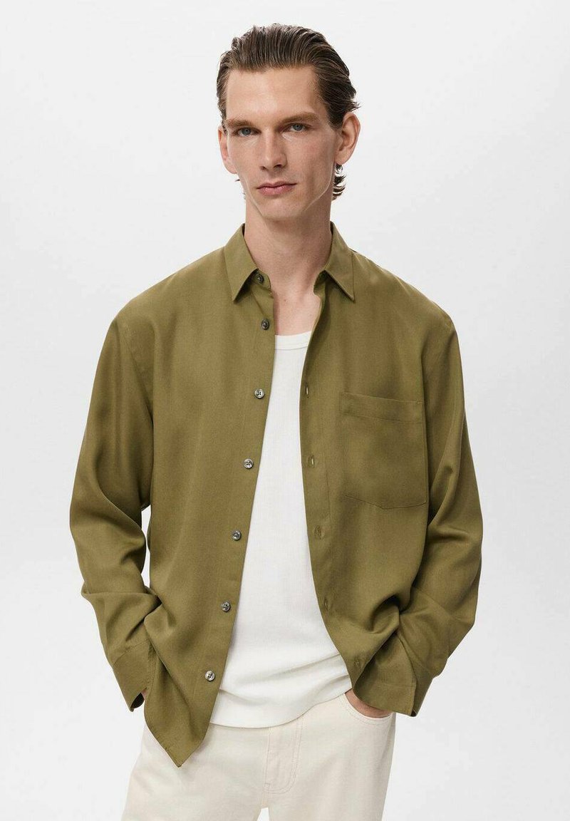 Olive green button-up shirt in smooth fabric, featuring a chest pocket and silver buttons, paired with a white crew neck t-shirt underneath.
