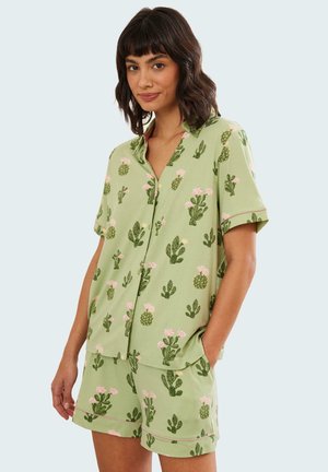 Set di pigiama verde a maniche corte con motivo di cactus e fiori rosa. La maglietta ha un colletto e bottoni; i pantaloni corti hanno una vita elastica.
