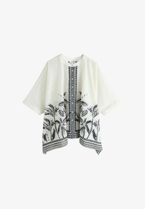 Blouse blanche à manches courtes avec imprimé noir de palmiers en bas et une bande verticale à motifs au centre devant.