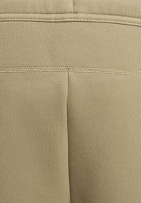 Beige sportleggings med en mjuk textur, med en hög midja och kontrasterande sömmar längs baksidan.