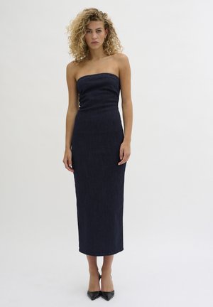 Strapless, fitted denim dress in dark blue, knee-length; features a straight silhouette and smooth texture, worn with black pointy heels.