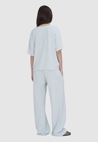 Lichtblauw, zacht stoffen lounge-outfit bestaande uit een oversized top met korte mouwen en een broek met wijde pijpen, met zakken en een ontspannen silhouet.