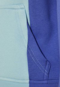 Felpa con cappuccio a blocchi di colore caratterizzata da un design blu chiaro e blu scuro. Realizzata in morbido tessuto testurizzato, presenta una tasca a marsupio e cuciture a contrasto.