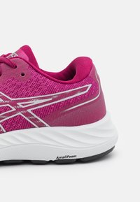 Scarpa sportiva rosa con una parte superiore in tessuto testurizzato, intersuola bianca e suola nera. Presenta accenti riflettenti e il marchio "AmpliFoam" sulla suola.