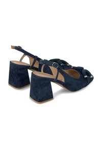 Granatowe zamszowe szpilki z blokowym obcasem, odkrytym palcem, regulowanym paskiem na kostkę oraz dekoracyjnym węzłem z przodu.