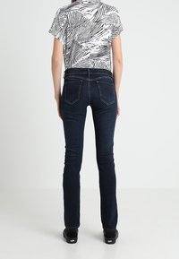 Top corto a maniche corte a motivi in bianco e nero abbinato a jeans fitted blu scuro, con un classico design a cinque tasche e dettagli di cucitura sottili.