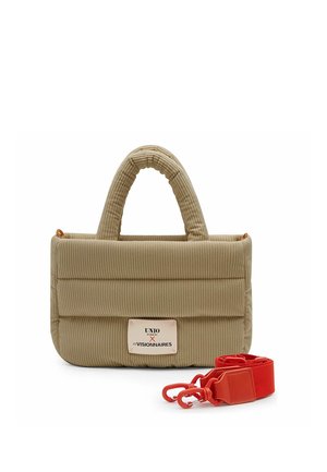 Beige gewatteerde corduroy handtas met dubbele handvatten, voorlabel en een afneembare felrode band met haken ernaast.