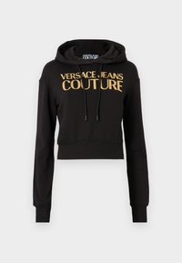 Svart kortärmad hoodie gjord av mjukt tyg, med en guld "VERSACE JEANS COUTURE"-logotyp och justerbara dragsnören på huvan.