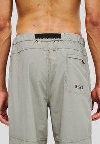 Ljusgrå shorts gjorda av texturerat tyg, med ett elastiskt midjeband, en bakficka och en tryckt etikett "B-583."