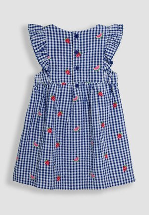 Mėlyna ir balta langeliais suknelė su raukiniais ant rankovių, siuvinėtomis braškėmis ir arbūzais, turi mygtukų užsegimą nugaros dalyje ir platėjančią sijoną.