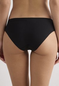 Černé spodní díly bikin s nízkým střihem, vyrobené z hladké látky a se bezšvými okraji pro čistý a elegantní vzhled.