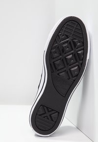 Sole di sneaker nera in gomma con un motivo a spina di pesce e a diamante, caratterizzata da accenti bianchi e branding sul tallone. Testurizzata per una migliore aderenza.