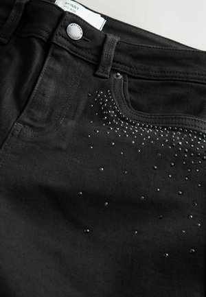 Czarne skinny jeans wykonane z denimu, z średnim stanem, z metalowym zapięciem i dekoracyjnymi kryształkami w gradientowym wzorze.