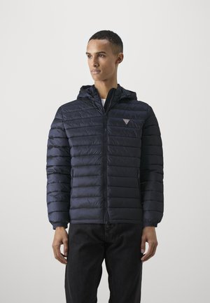 Navy blue puffer jacket with a zip front, elastic cuffs, and a hood. Features a small logo on the chest and quilted pattern throughout.