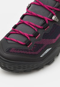 Musta vaelluskengät, joissa on teksturoitu pinta, vaaleanpunaiset nauhat ja FLEXTRON-yksityiskohta sivulla. Kengässä on kestävä, tukevat pohjat.