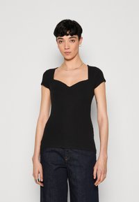 Haut noir à manches courtes côtelé avec un décolleté carré et une silhouette ajustée. Design simple avec un tissu texturé et sans motifs visibles.