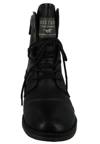 Černá kožená kotníková bota s šněrovacím designem, bočním zipem a texturovanými detaily. Prošité akcenty a značková etiketa na jazyku.