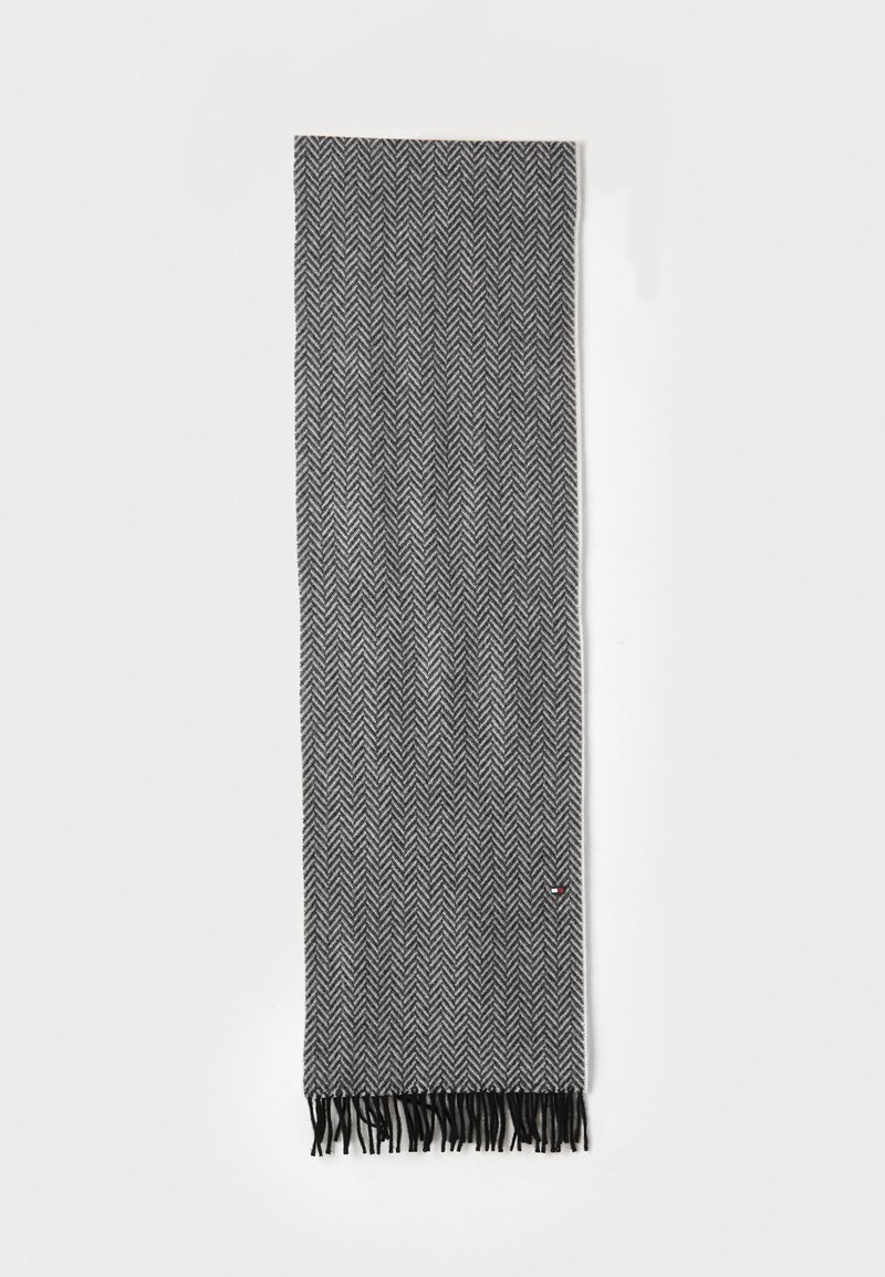 Foulard en noir et gris à motif en chevron, fabriqué en tissu doux, avec des franges aux extrémités. Forme longue et rectangulaire.