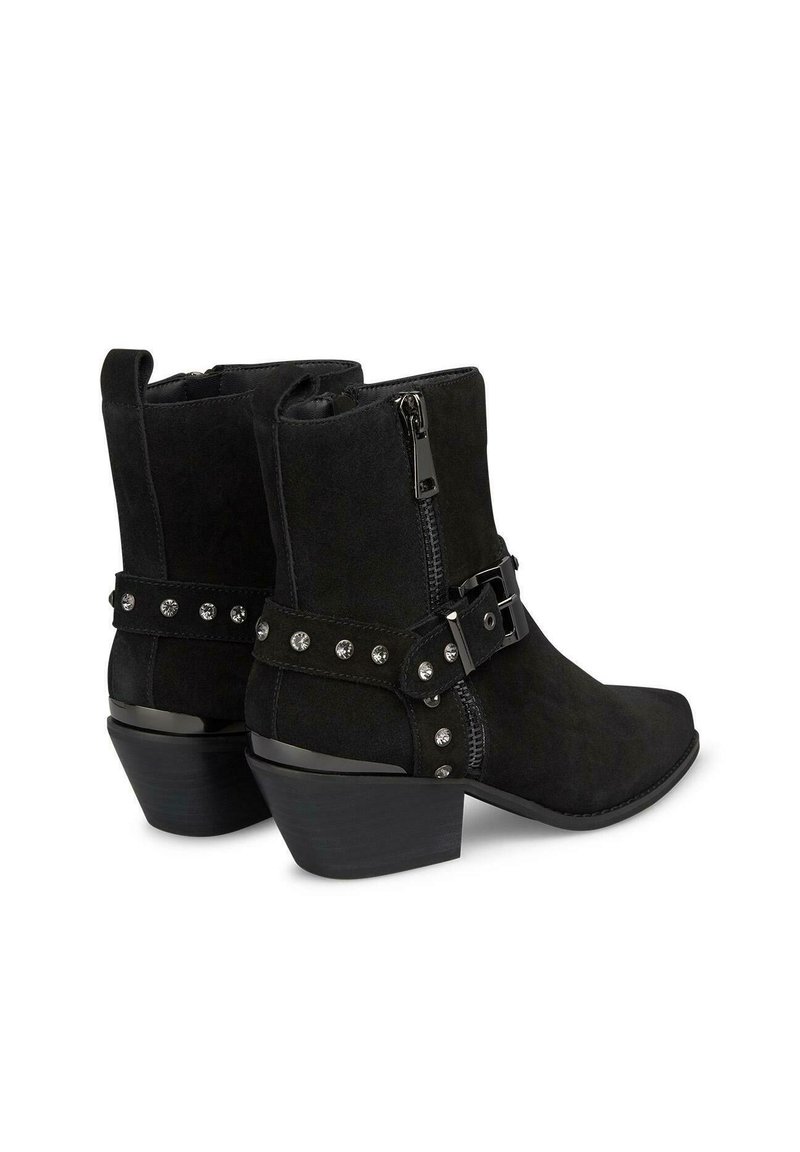 Stivali alla caviglia in suede nero con punta affusolata, cerniera laterale e nastro decorativo con borchie argentate. Tacco spesso per maggiore stabilità.