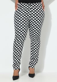Zwart-witte polkadotbroek met een getailleerd ontwerp en een gladde textuur. Heeft een klassieke knoopsluiting en een tapering fit tot op de enkel.