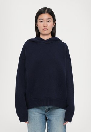 Navy blue hooded sweatshirt with a loose fit, ribbed cuffs, and hem. Features two front pockets and soft knit texture.