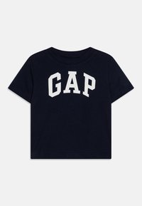 Tamsiai mėlynas medvilninis marškinėliai su trumpomis rankovėmis, turintys didelį baltą "GAP" Logotipą per krūtinę ir apvalią iškirptę.