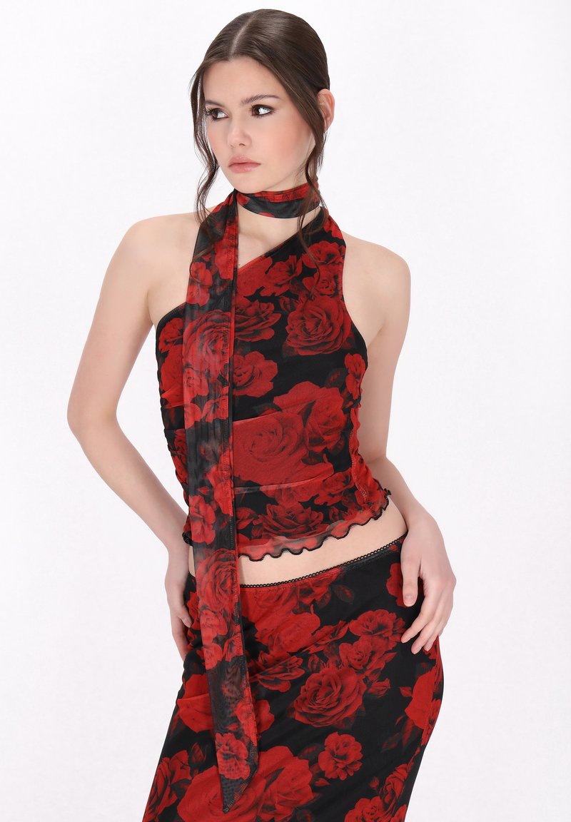 Schwarzes Blumenshirt mit Neckholder und rotem Rosenmuster, ausgestattet mit einer transparenten Schalschnur und einem geschwungenen Saumdetail, kombiniert mit einem passenden Rock.