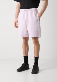 Lyserøde svedshorts med elastisk talje og snor, med sidelommer og broderet "HUGO" logo på forsiden.