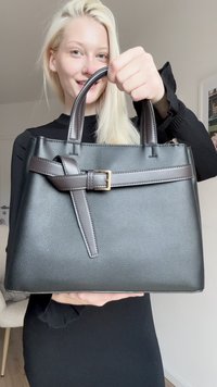 Borsa nera con texture, dal design strutturato, dotata di due manici e una tracolla marrone decorata con una fibbia dorata.