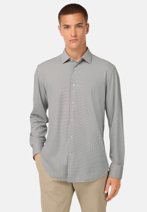 Chemise à manches longues gris clair avec un motif à carreaux discret, col classique et patte de boutonnage. Tissu lisse et coupe standard.