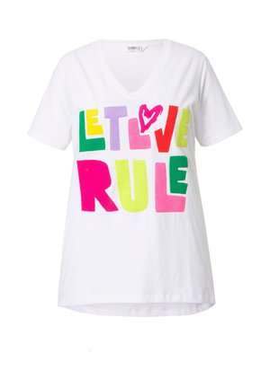 Bílý bavlněný tričko s V-výstřihem a výraznými, vícebarevnými písmeny, které hlásají "NECHTE LÁSKU VLÁDNOUT," s akcentem v podobě růžového srdce.