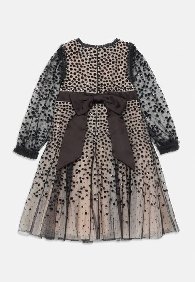 Vestido de manga larga beige con superposición de malla negra con lunares, lazo negro en la cintura y cierre de cremallera en la parte trasera.