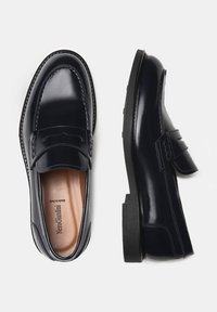 Mocasines de cuero azul marino con un acabado suave, detalles de costura y un acento de correa. Cuentan con una suela de goma ligera.