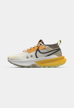 Lightweight running shoe with a beige and yellow upper, mesh and synthetic materials, prominent black logo, textured sole with vibrant accents.