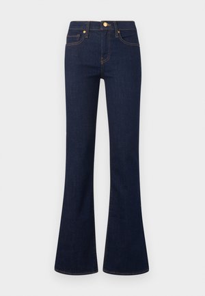 Jean bootcut bleu foncé avec bouton frontal, fermeture éclair, passants de ceinture et coutures contrastées sur un fond clair uni.