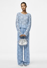 Light blue lace two-piece set with long-sleeved top and wide-leg pants, paired with a small silver handbag and matching blue shoes.