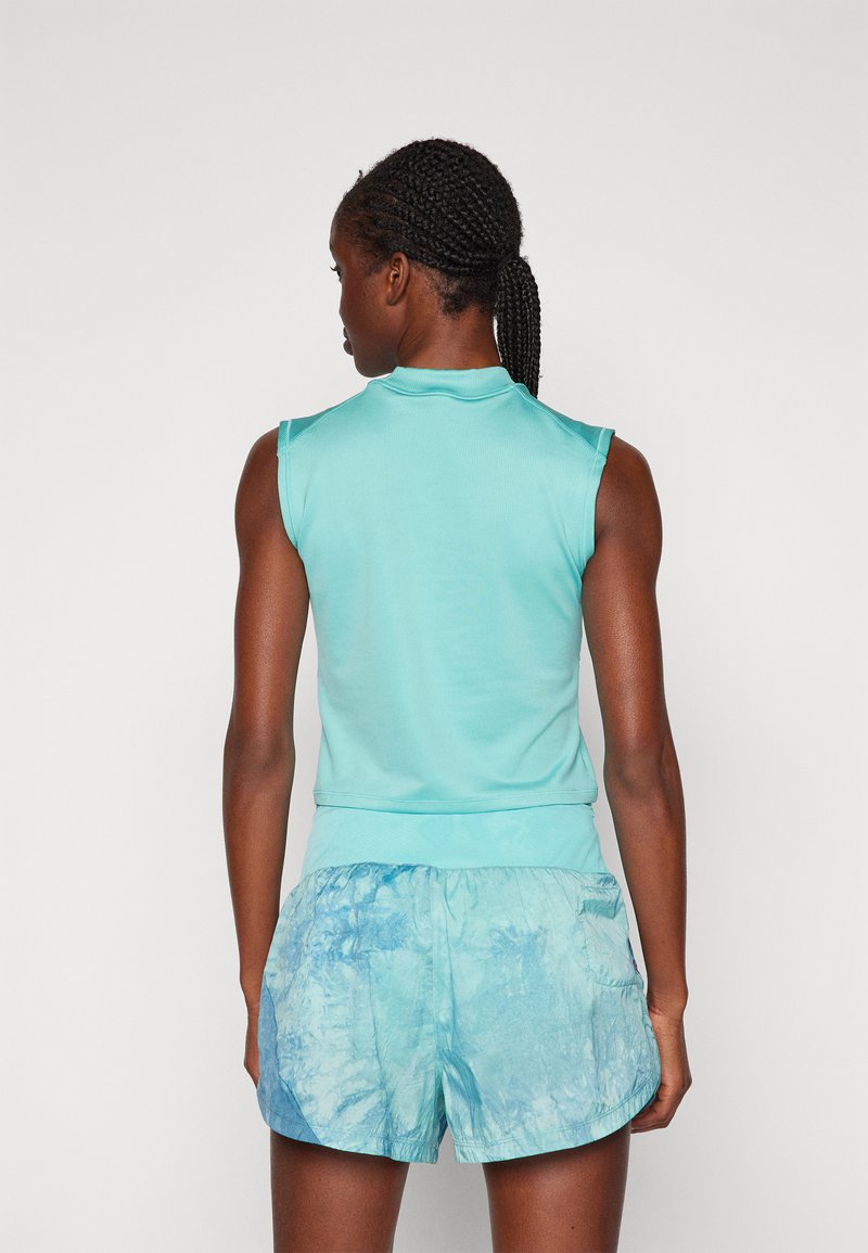 Haut sans manches bleu clair avec un col haut, associé à un short en tie-dye dans des teintes similaires de bleu, avec une taille élastique.