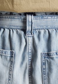 Světle modré denimové šortky s nařaseným pasem. Obsahují dvě kapsy a viditelné švy. Jednoduchý design, bez vzorů nebo akcentů.