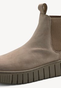 Bottines en daim beige avec panneaux latéraux élastiques et languette. Semelle en caoutchouc épaisse et texturée avec des rainures verticales. Fini lisse sur le dessus.