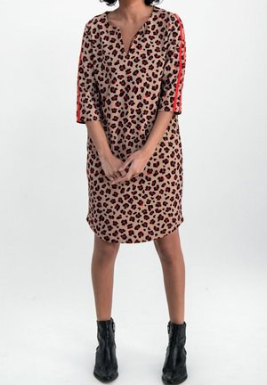 Robe à motif léopard beige avec des accents rouges, mi-longue avec un décolleté en V et des manches trois quarts, associée à des bottines noires.