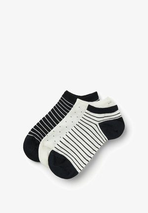 Drei Paar Socken: ein einfarbiges schwarzes Paar, ein cremfarbenes mit schwarzen Punkten und ein cremfarbenes mit schwarzen Streifen. Alle haben kontrastierende schwarze Bündchen.