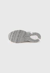 Gray rubber sneaker sole with a textured tread pattern and white accents. Features durable materials and a flexible design for grip.