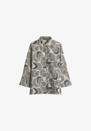 Langarmshirt van een lichtbeige stof met een zwart abstract golvend patroon, knopen aan de voorkant en een puntige kraag.