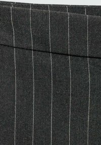 Svart tyg med vita pinstripe, med en mjuk textur och en vikt fåll överst.