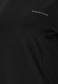 Schwarzes T-Shirt aus Stoff mit strukturierter Oberfläche und einem kleinen grauen "ENDURANCE"-Logo auf der oberen linken Seite.