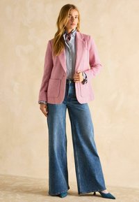 Roosa linane bleiser kahe esiseotud taskuga, kombineeritud triibulise sinise ja valge särgiga. Laiad sinised teksad ja smaragdrohelised terava ninaga kontsad.