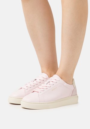 Light pink leather sneakers with a white sole, featuring laces, subtle branding, and a neutral-colored heel accent. Smooth texture.