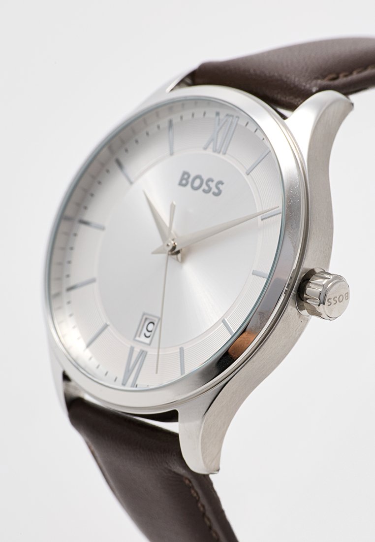 Silberne Zifferblatt-Uhr mit braunem Lederarmband, ausgestattet mit römischen Ziffern, Datumsanzeige und einem Gehäuse aus Edelstahl mit Krone.